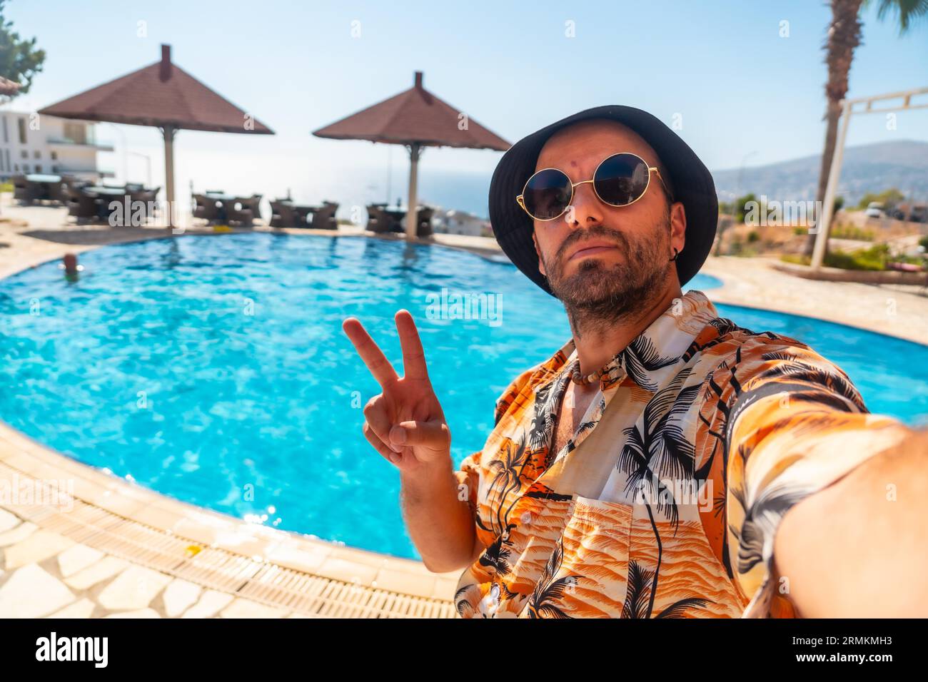 Turista nella piscina dell'hotel in estate che si prende un selfie godendosi la vacanza Foto Stock