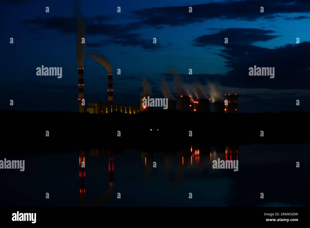 Vista notturna di una centrale a carbone. Le luci della centrale elettrica si riflettono nel lago. Costi dell'elettricità elevati. Foto scattata di notte con l Foto Stock
