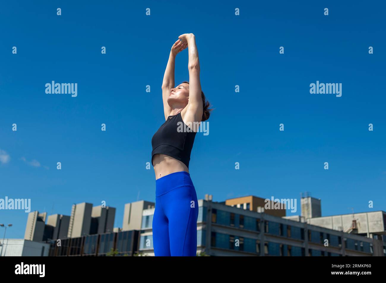 La donna allunga le braccia sopra la testa mentre si prepara all'esercizio Foto Stock