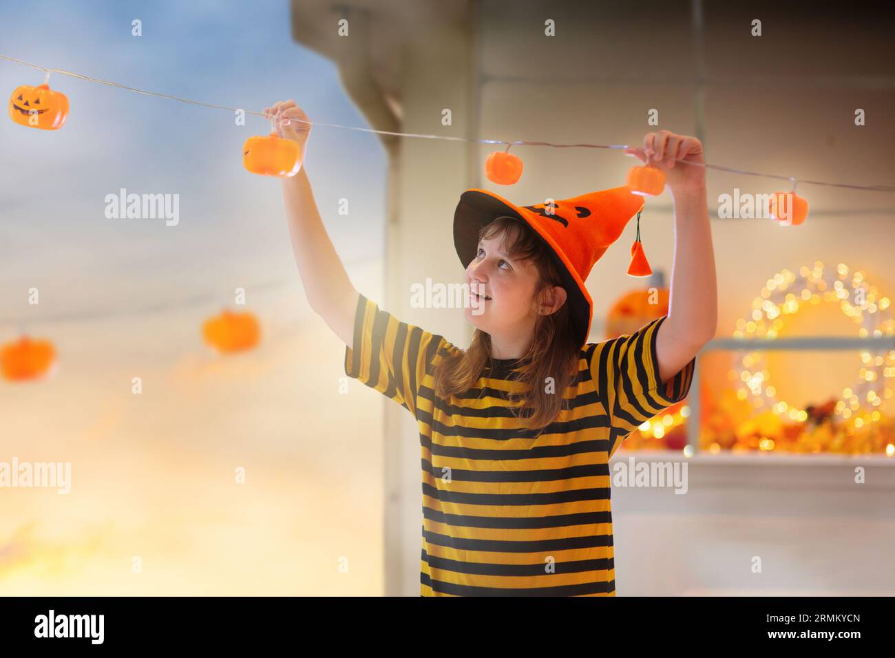 Casa decorata per famiglie per festeggiare Halloween. I bambini e la madre appendono le luci della lanterna di zucca per decorare con cura. I bambini decorano la casa. Bambini Foto Stock