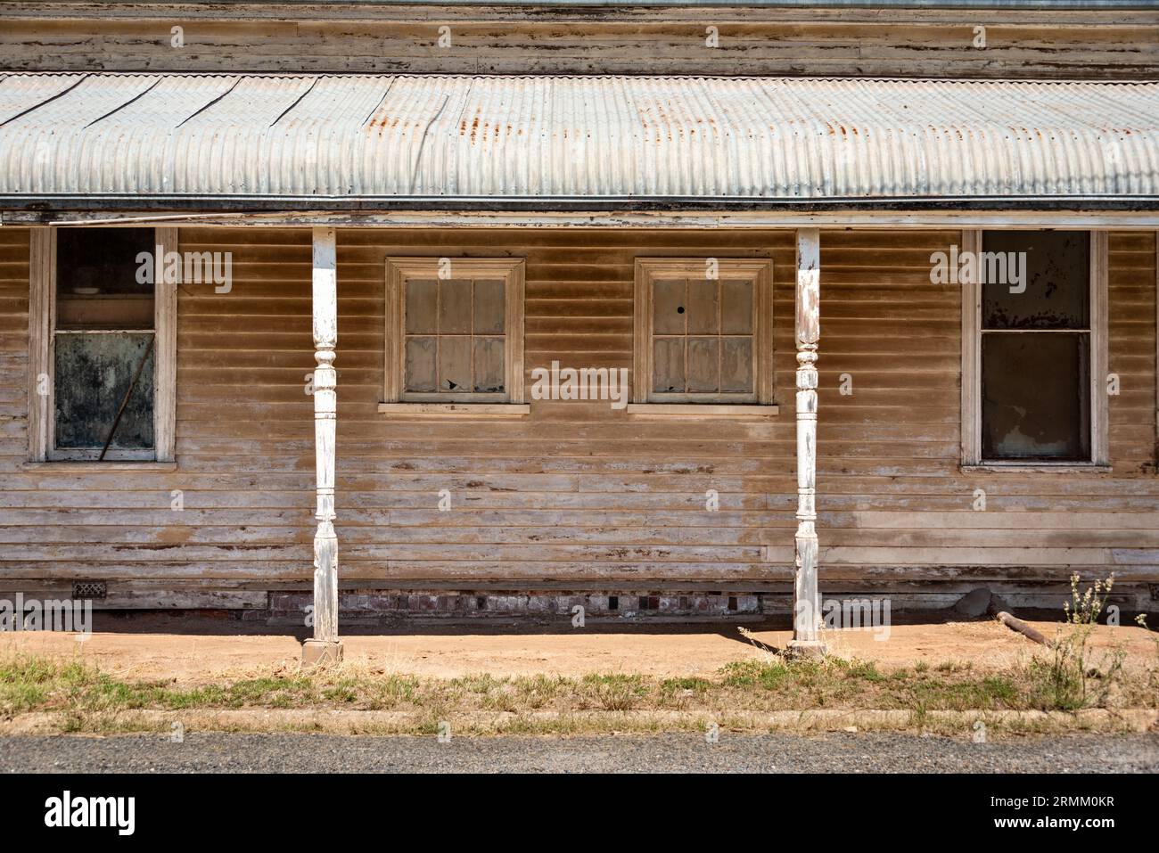Un'antica casa di legno sbiadita e dipinta con sbiadito in una città rurale nel Victoria, Australia, con finestre simmetriche e tetto del patio ondulato Foto Stock