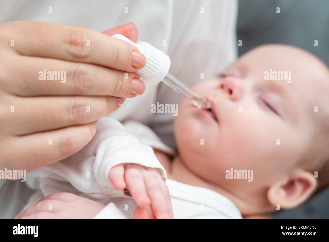La madre amministra gocce orali al neonato, concetto di garantire la salute del bambino Foto Stock