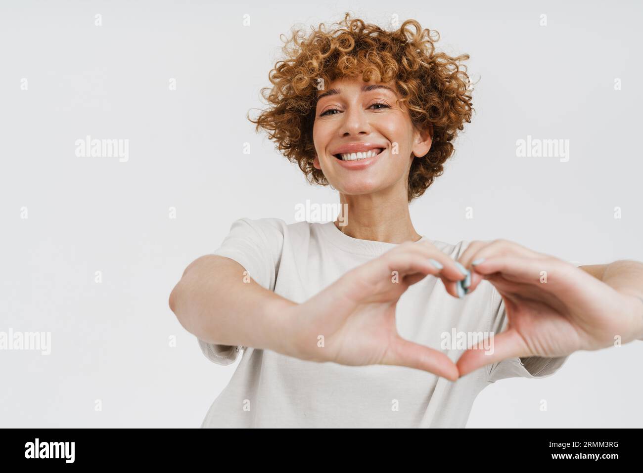Allegra zenzero maturo fa un gesto cardiaco isolato su sfondo bianco Foto Stock