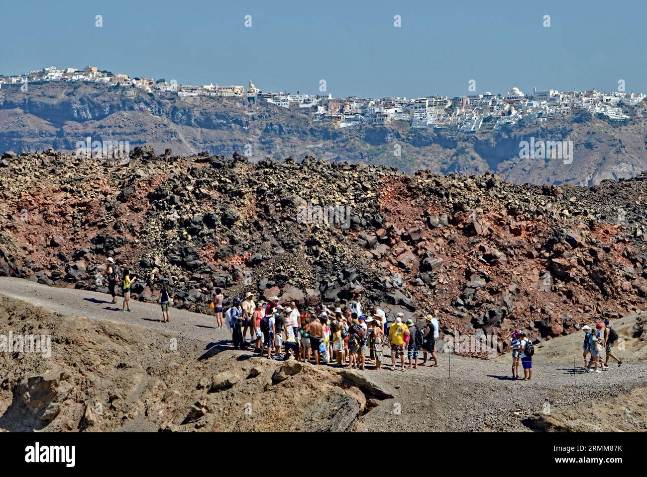 La folla di persone sale al vulcano dell'isola di Santorini Nea Kameni. Ammira la città di Oia sulla scogliera. Vacanze estive in Grecia. Foto Stock