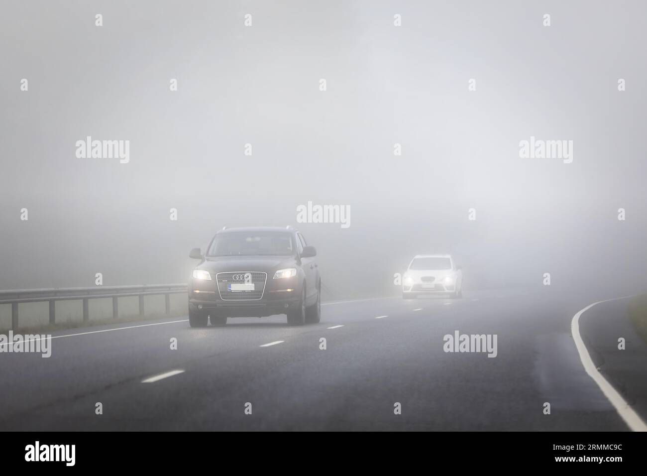 Vetture che viaggiano in autostrada, che appaiono attraverso la fitta nebbia. Salo, Finlandia. 25 agosto 2023. Foto Stock