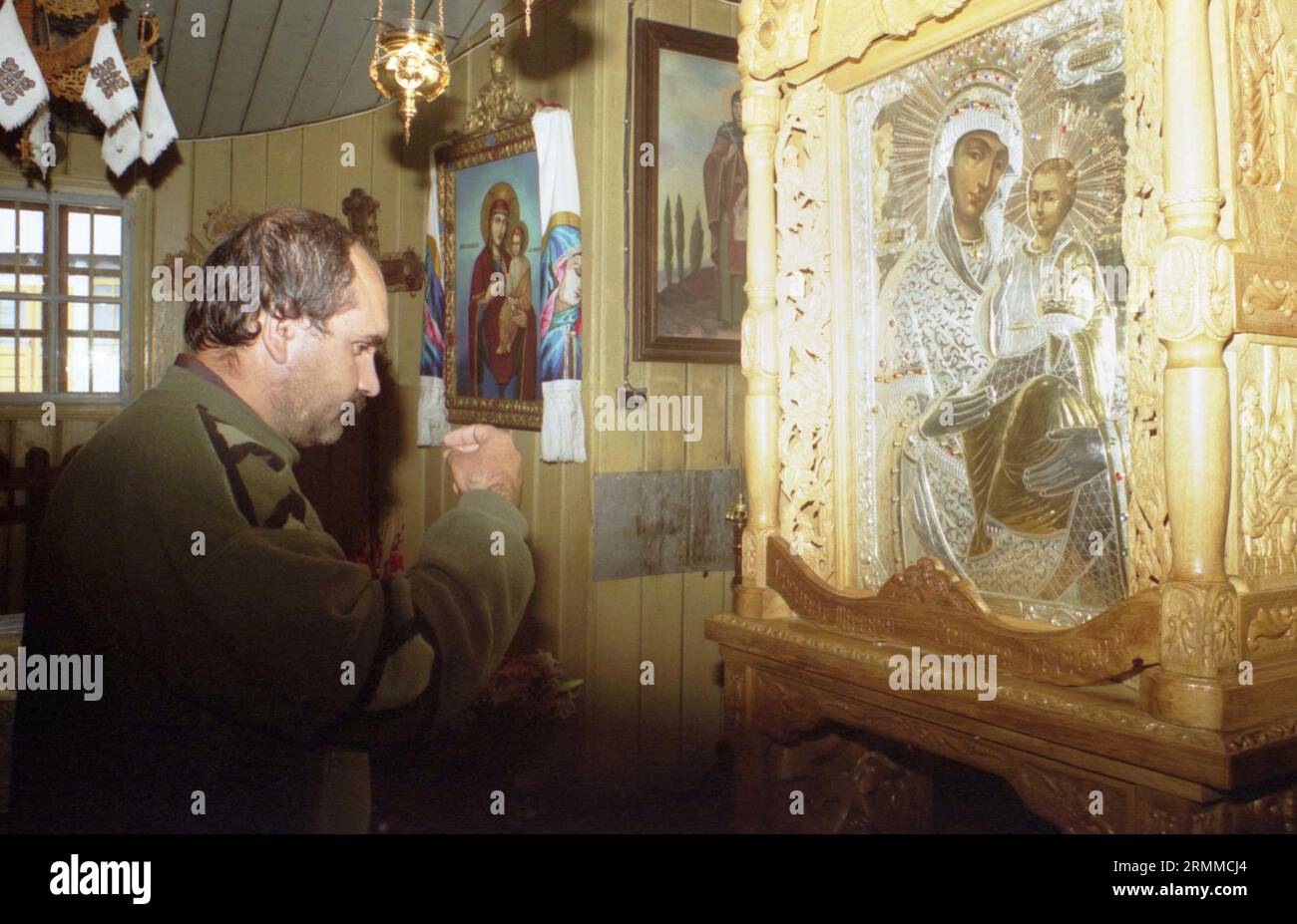 Monastero di Rarau, Contea di Suceava, Romania, circa 2000. L'uomo che fa il segno della croce davanti all'icona ortodossa raffigurante la madre di Dio con il Santo bambino, considerato un'icona miracolosa. Foto Stock