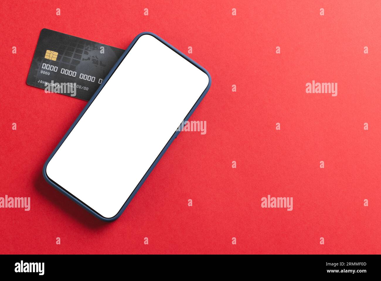 Smartphone con schermo vuoto e carta di credito su sfondo rosso Foto Stock