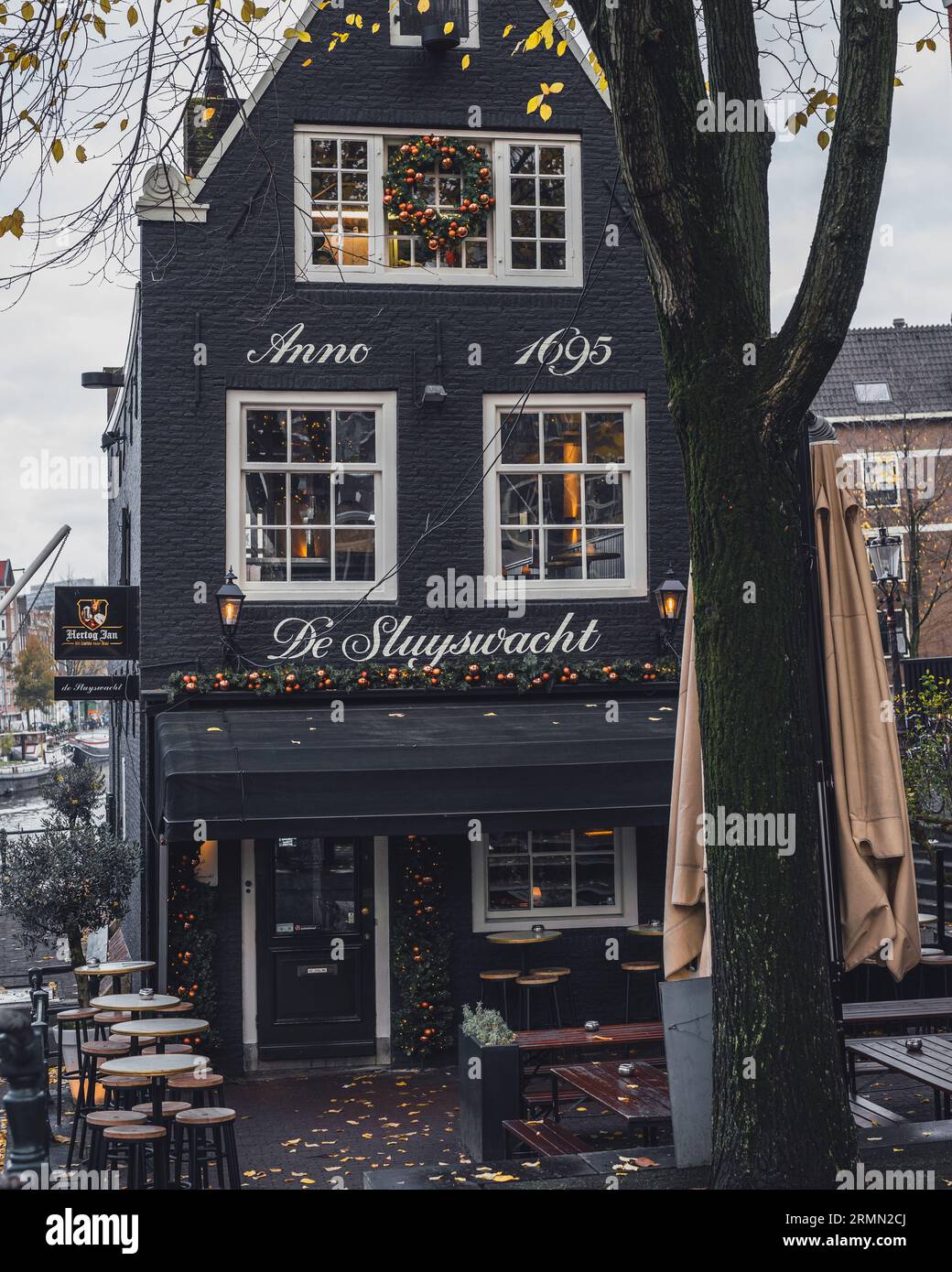 Amsterdam, Paesi Bassi - novembre 27 2022: Pittoresco e bellissimo caffè De Sluyswacht, vicino a un canale di Amsterdam in un grigio giorno autunnale. Foto Stock