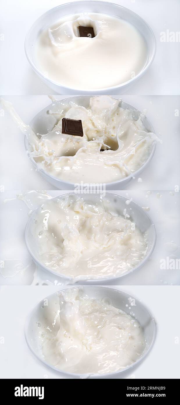 Cioccolatini che cadono in una ciotola del latte su sfondo bianco Foto Stock