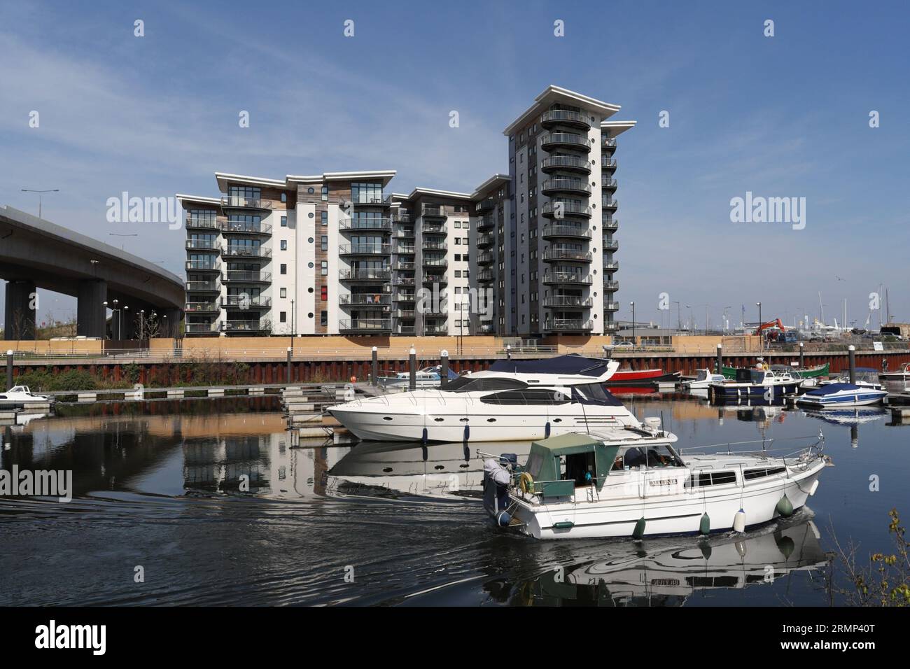 Barche sul fiume Ely nella baia di Cardiff, Galles, con moderni appartamenti lungo il fiume. Foto Stock