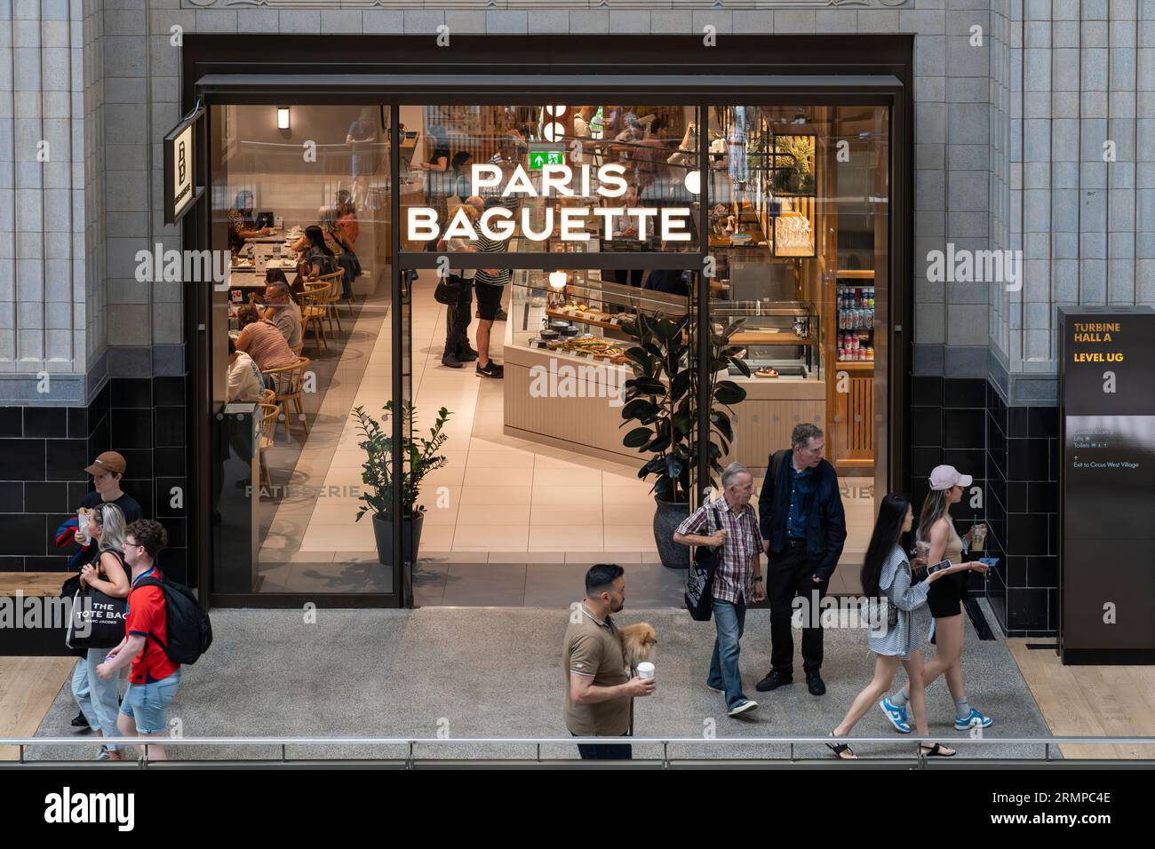 Persone che mangiano in un caffè della panetteria Paris baguette nella turbine Hall A all'interno del rinnovato sito di sviluppo della centrale elettrica di Battersea. Londra, Inghilterra Foto Stock
