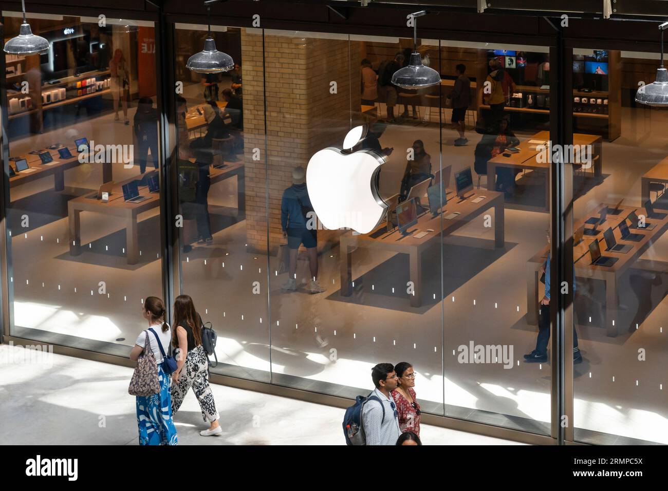 Gli acquirenti che esplorano i prodotti Apple in un Apple Store nello sviluppo rinnovato della Battersea Power Station con il logo Apple in evidenza. Londra, Regno Unito Foto Stock