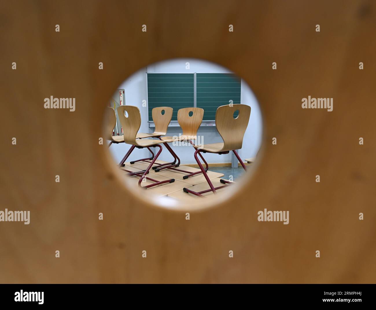 Wiesbaden, Germania. 29 agosto 2023. Attraverso il buco sul retro di una sedia, le sedie possono essere viste in piedi sui tavoli in una classe della Robert Schumann Elementary School. Secondo le stime attuali del GEW, le scuole dell'Assia hanno accumulato investimenti necessari per almeno cinque miliardi di euro. (A dpa: "Union: School investment backlog ammonta a cinque miliardi di euro") credito: Arne Dedert/dpa/Alamy Live News Foto Stock