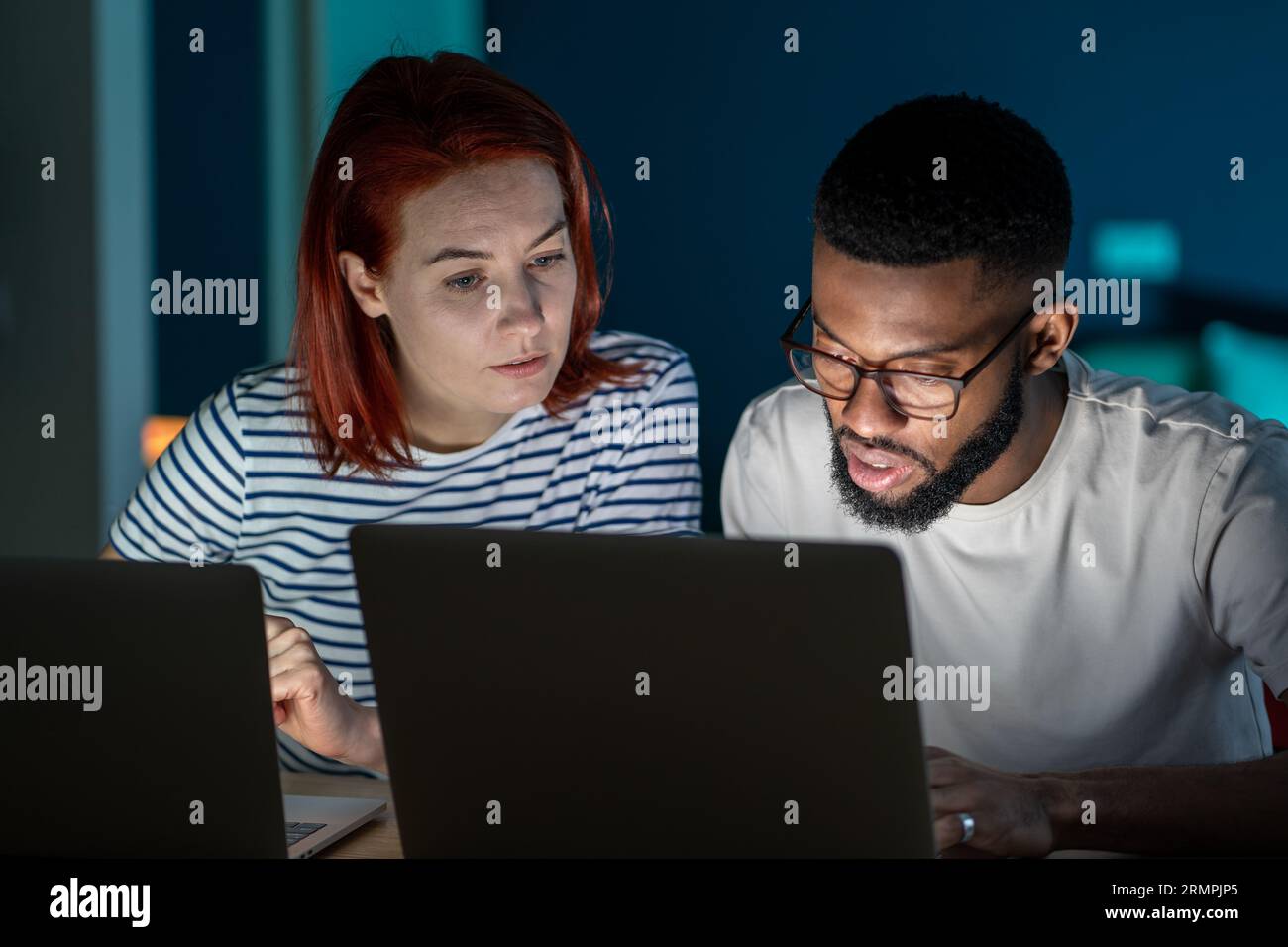 Famiglia moglie marito che fa la routine di vita sui portatili a casa la sera consigliando di discutere insieme. Foto Stock