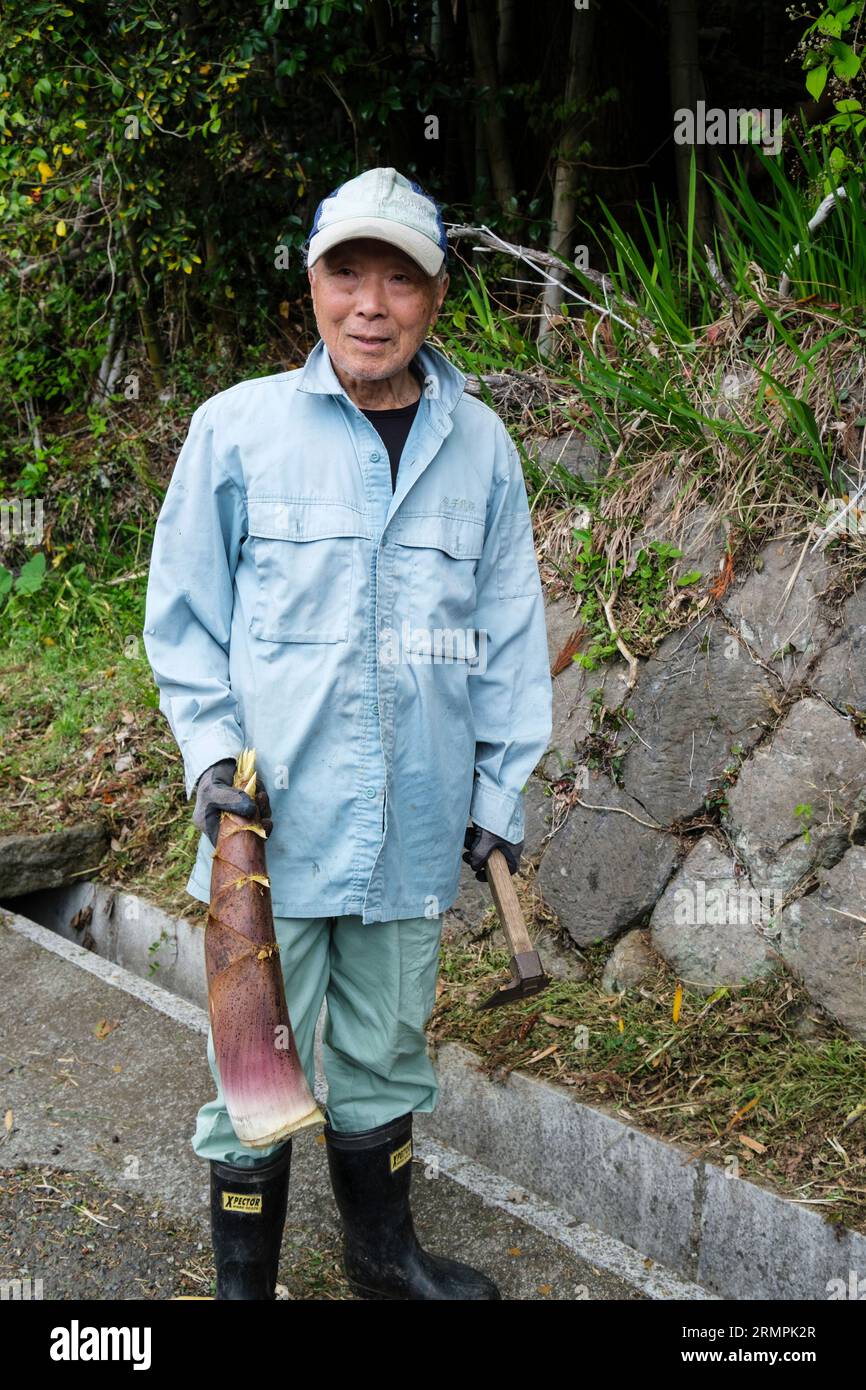 Giappone, Kyushu. Uomo che mostra il colpo di bambù che ha appena raccolto. Foto Stock