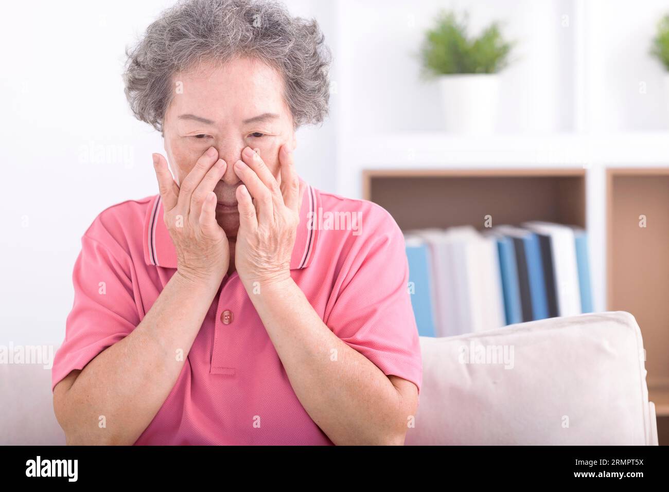 Frustrata e stressata nonna anziana che soffre di vista offuscata, dolore agli occhi affaticato. Foto Stock