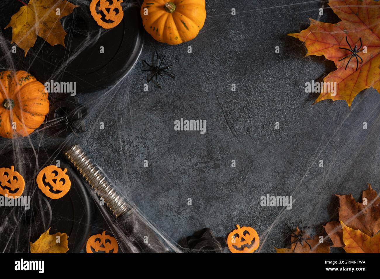 Piastre di peso a campana, zucche di Halloween, ragni, ragnatela, foglie autunnali. Palestra, allenamento sportivo, piatto autunno con spazio fotocopie. Foto Stock