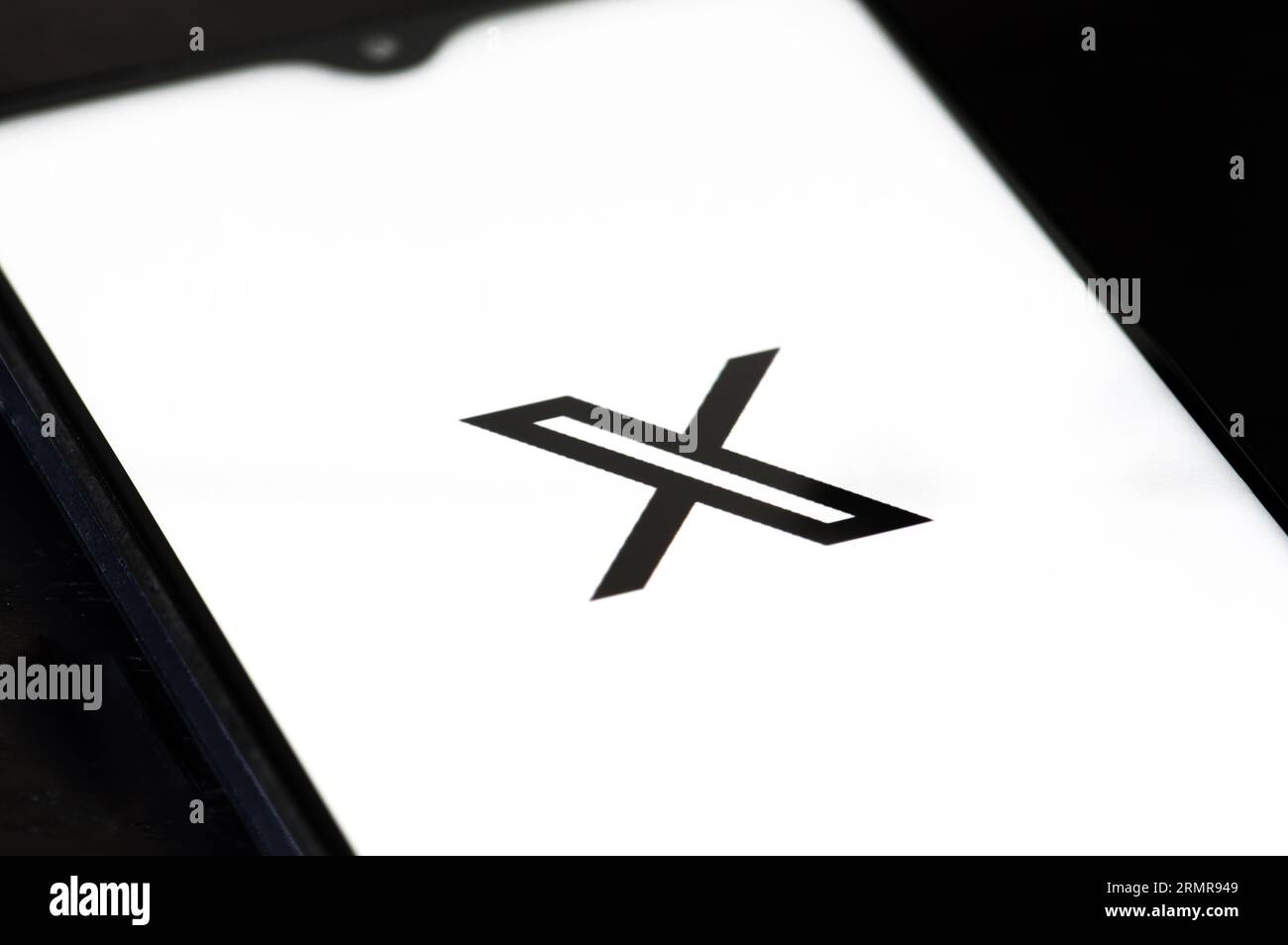 Logo iniziale di Twitter o X e app su uno smartphone su sfondo bianco. Social media online e servizio di social network di proprietà di Elon Musk Foto Stock