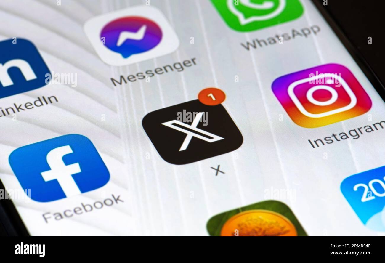 Logo iniziale di Twitter o X e app su uno smartphone. Social media online e servizio di social networking con notifica rossa e altre app Foto Stock