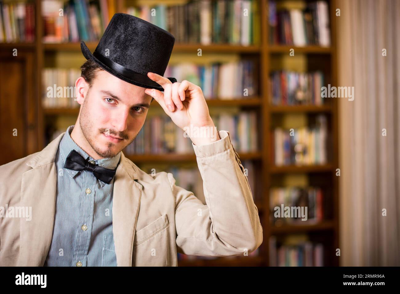 Un uomo che indossa un cappello davanti a una libreria Foto Stock