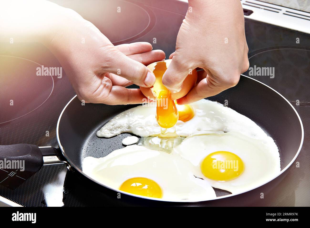 La donna rompe un uovo nelle uova fritte da vicino Foto Stock