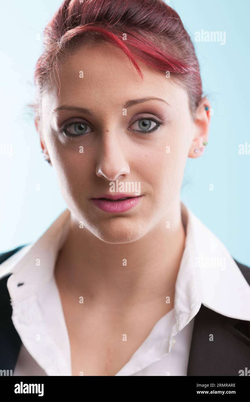 La giovane rossa indossa un abito formale e una camicetta bianca aperta contempla le sue attività in ufficio sullo sfondo del suo posto di lavoro. Con gli occhi blu, trasuda con Foto Stock