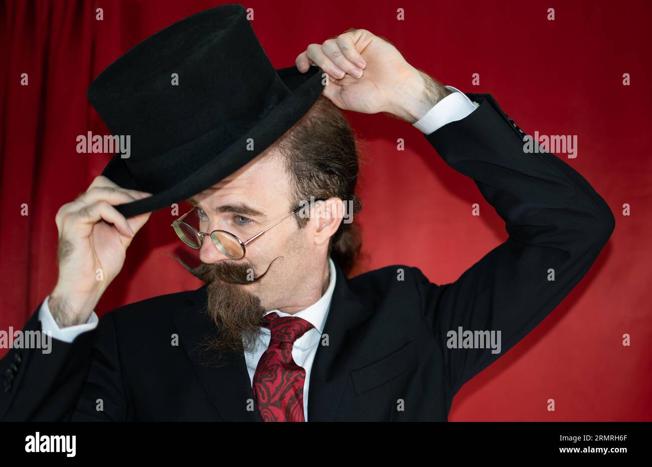 Mago caucasico d'epoca con cappello, occhiali e baffi in posa Foto Stock