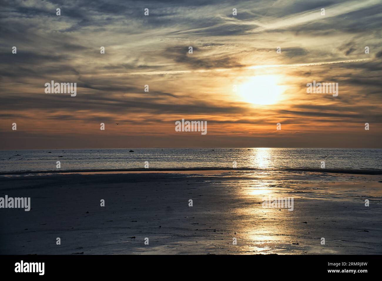 Tramonto, mare illuminato. Spiaggia sabbiosa in primo piano. Onde luminose. Isola di Poel sul Mar Baltico. Foto della natura dalla costa Foto Stock
