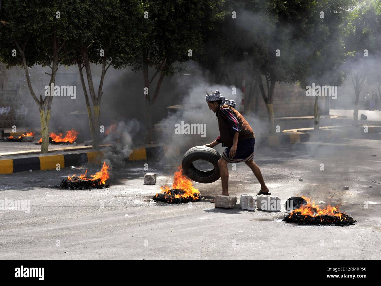 (140730) -- SANAA, 30 luglio 2014 -- Uno yemenita brucia pneumatici per protestare contro la decisione del governo di aumentare drasticamente il prezzo del carburante a Sanaa, Yemen, il 30 luglio 2014. Il governo yemenita aumentò il prezzo della benzina da 125 riyal yemeniti (0,58 dollari USA) a 200 riyal per litro e sbarcò da 100 riyal a 195 riyal mercoledì, cosa che ha scatenato proteste di massa nella capitale Sanaa. I manifestanti arrabbiati bruciarono pneumatici e tagliarono molte strade a Sanaa. Il governo ha schierato più soldati per mantenere la sicurezza nella capitale. ) (Dzl) YEMEN-SANAA-PREZZO DELLA BENZINA-PROTESTA MohammedxMohammed Foto Stock