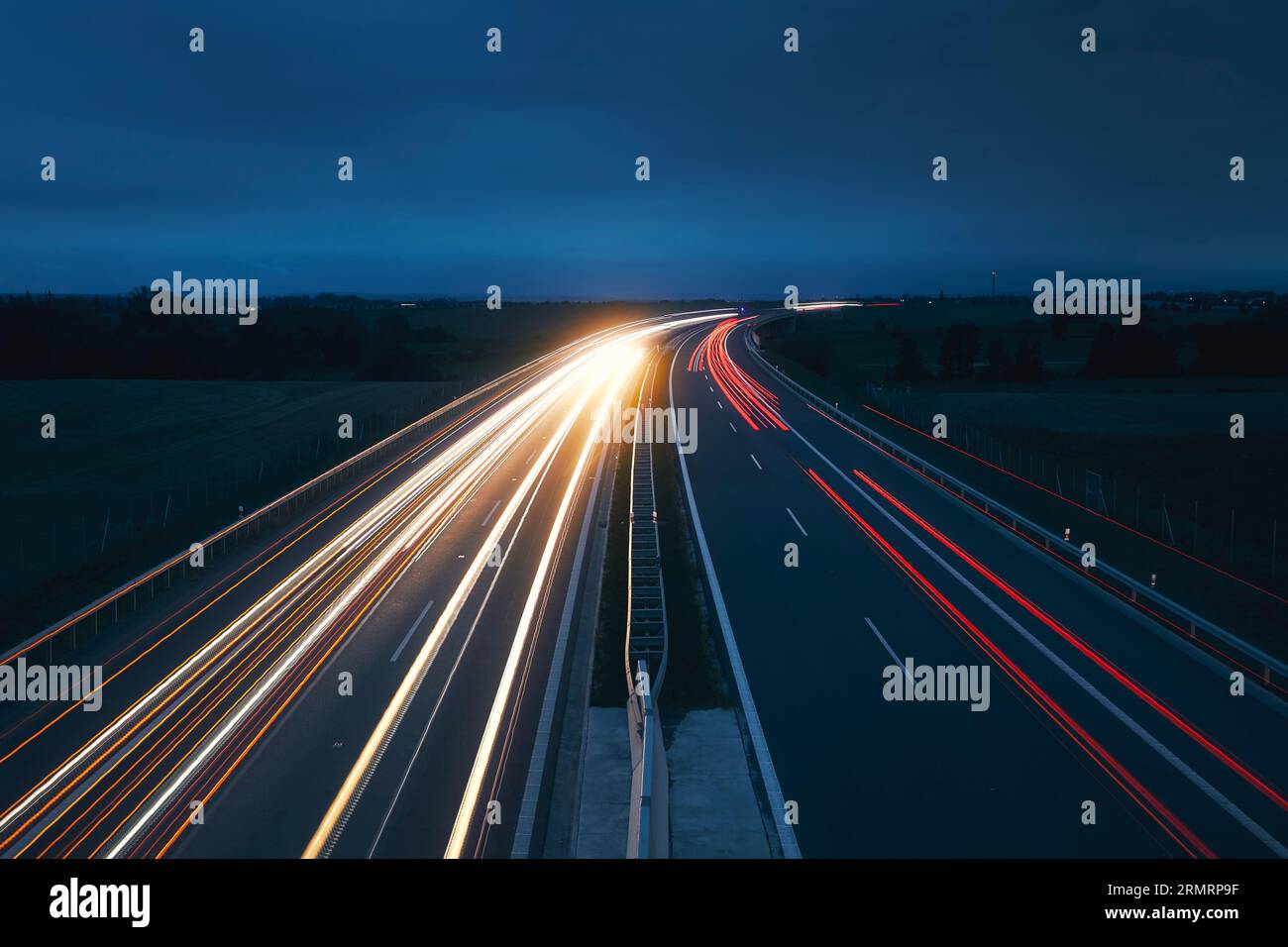 Autostrada trafficata in campagna di notte. Trasporto in auto a tema, indicazioni e collegamenti. Foto Stock