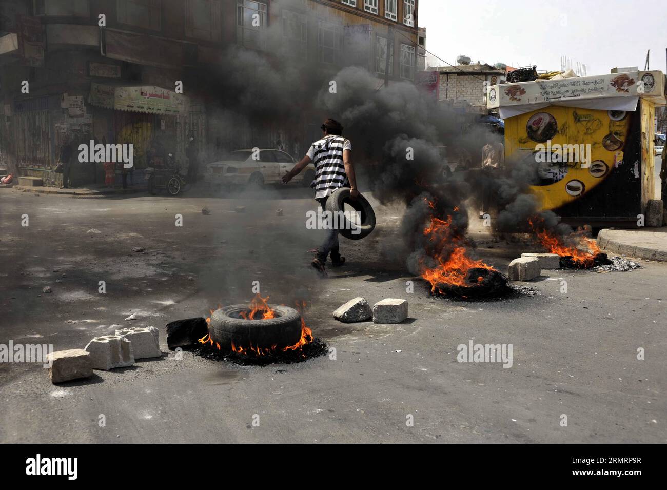 (140730) -- SANAA, 30 luglio 2014 -- Uno yemenita brucia pneumatici per protestare contro la decisione del governo di aumentare drasticamente il prezzo del carburante a Sanaa, Yemen, il 30 luglio 2014. Il governo yemenita aumentò il prezzo della benzina da 125 riyal yemeniti (0,58 dollari USA) a 200 riyal per litro e sbarcò da 100 riyal a 195 riyal mercoledì, cosa che ha scatenato proteste di massa nella capitale Sanaa. I manifestanti arrabbiati bruciarono pneumatici e tagliarono molte strade a Sanaa. Il governo ha schierato più soldati per mantenere la sicurezza nella capitale. ) (Dzl) YEMEN-SANAA-PREZZO DELLA BENZINA-PROTESTA MohammedxMohammed Foto Stock