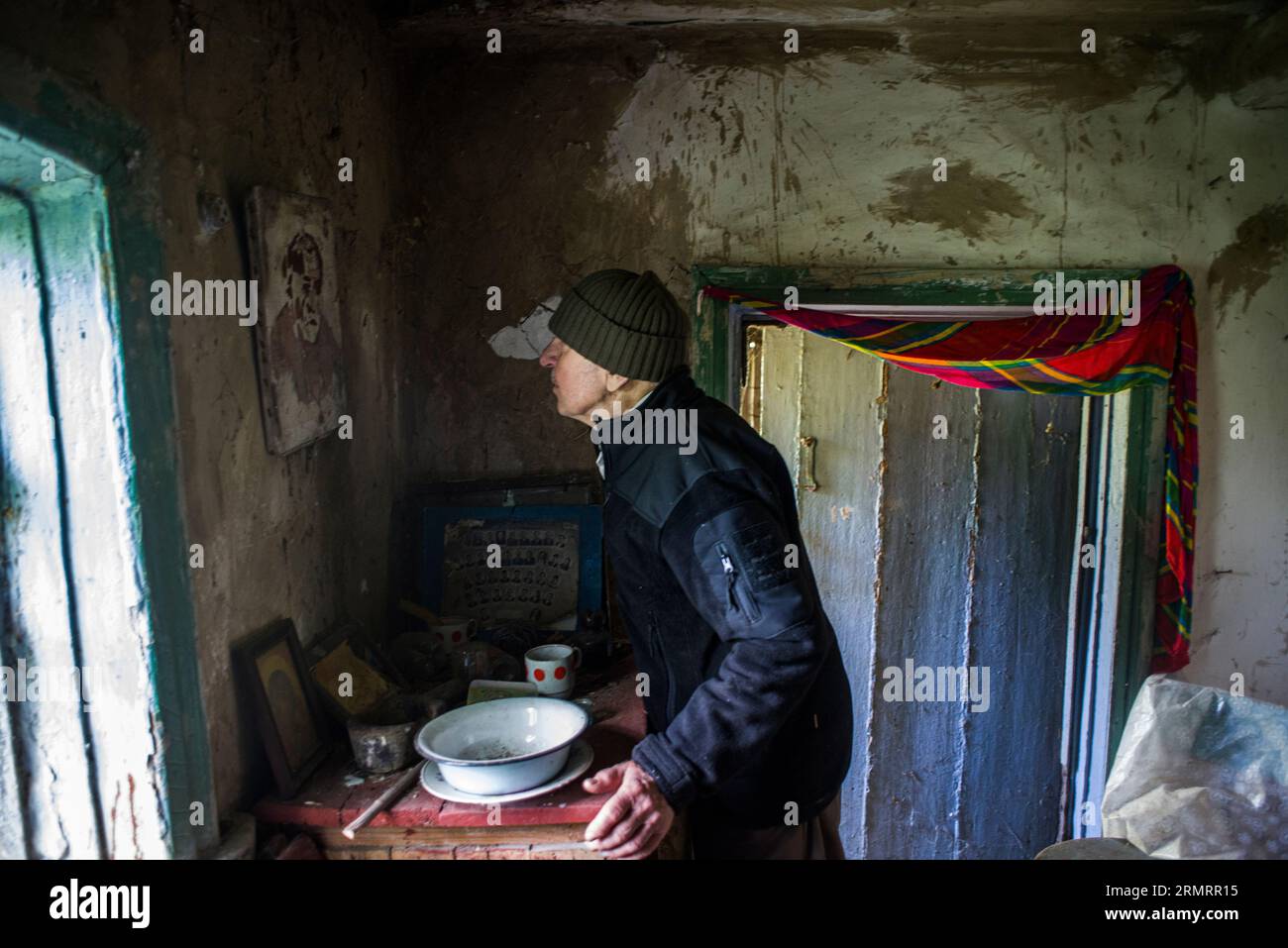 Un uomo anziano, vicino a una finestra nella sua capanna abbandonata Foto Stock