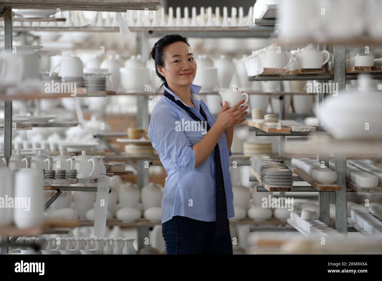 (140806) -- PECHINO, 6 agosto 2014 -- Zhang Lingyun acquista basi di ceramica incombusta a Jingdezhen, provincia dello Jiangxi della Cina orientale, 18 luglio 2014. Zhang Lingyun ha 40 anni. Sono passati 20 anni da quando l'artista ceramico è venuto a Jingdezhen, capitale della porcellana cinese. La storia di Zhang con la ceramica ebbe un inizio casuale e romantico: Sapeva quasi nulla di ceramica prima di imbattersi nel nome Jingdezhen Ceramic Institute (JCI) quando si iscriveva al college. La ceramica sembrava interessante, quindi ho presentato la domanda per la JCI. Il capriccio d'impulso aveva fatto una grande differenza nella vita di Zhang. Il suo primo contatto con Foto Stock