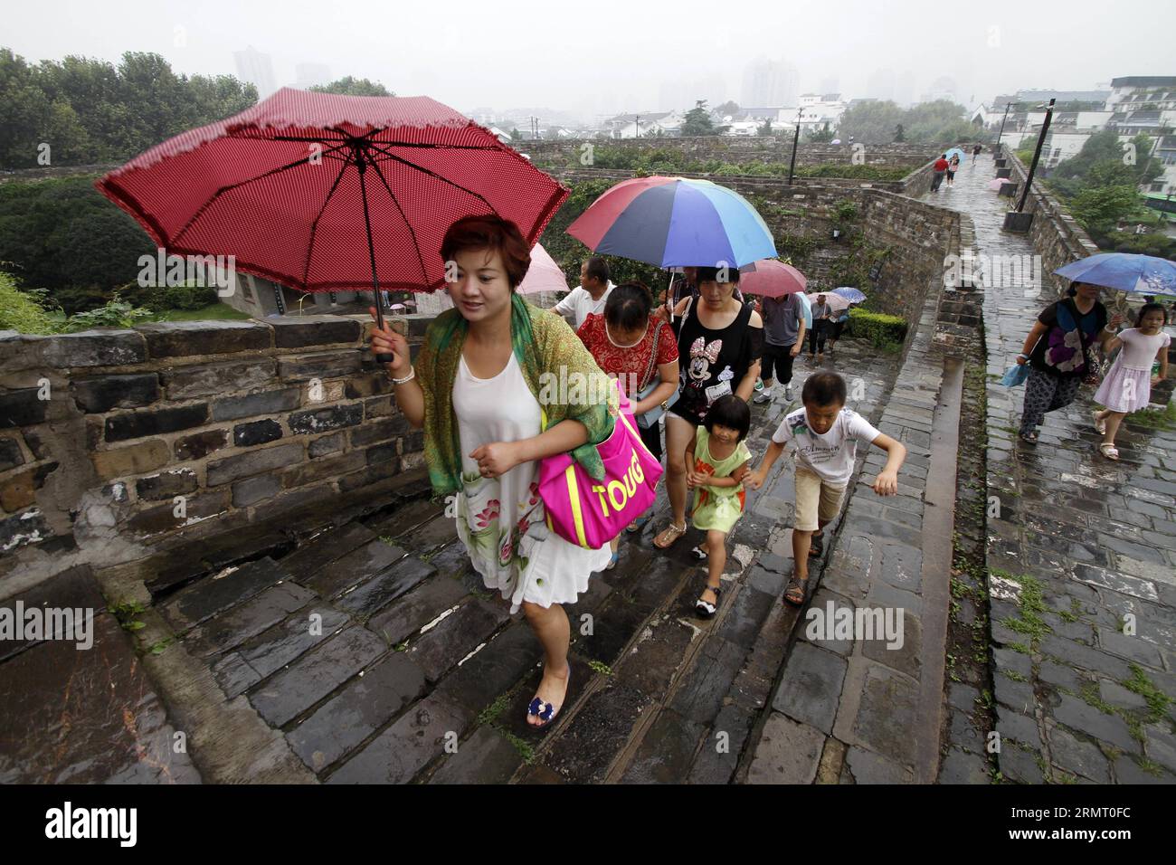 I turisti visitano la porta di Zhonghuamen, un barbacano che fa parte dell'antica cinta muraria della città di Nanchino, capitale della provincia di Jiangsu della Cina orientale, 8 agosto 2014. Le mura della città di Nanchino furono costruite tra il 1366 e il 1386, i primi anni della dinastia Ming (1368-1644). Un tempo capitale della dinastia, Nanchino era racchiusa da quattro strati di mura cittadine in mattoni di pietra. Dopo sei secoli di erosione naturale e distruzione umana di proposito, la lunghezza delle mura rimanenti ammonta a 25 chilometri, che ancora oggi fanno un record mondiale. () (LMM) CHINA-JIANGSU-NANJING-CITY WALL-TOURISM (CN) XINHUA PUBLIC Foto Stock