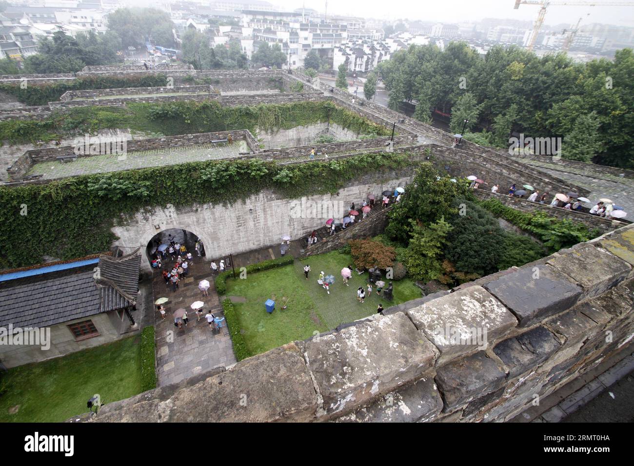 I turisti visitano la porta di Zhonghuamen, un barbacano che fa parte dell'antica cinta muraria della città di Nanchino, capitale della provincia di Jiangsu della Cina orientale, 8 agosto 2014. Le mura della città di Nanchino furono costruite tra il 1366 e il 1386, i primi anni della dinastia Ming (1368-1644). Un tempo capitale della dinastia, Nanchino era racchiusa da quattro strati di mura cittadine in mattoni di pietra. Dopo sei secoli di erosione naturale e distruzione umana di proposito, la lunghezza delle mura rimanenti ammonta a 25 chilometri, che ancora oggi fanno un record mondiale. () (LMM) CHINA-JIANGSU-NANJING-CITY WALL-TOURISM (CN) XINHUA PUBLIC Foto Stock
