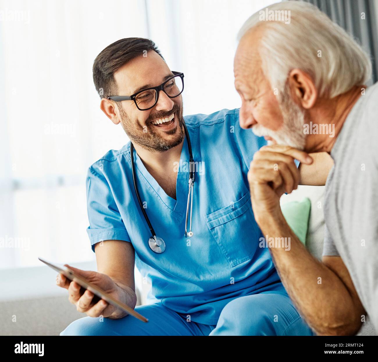 medico infermieristico assistenza senior tablet tecnologia che mostra caregiver aiuto assistenza pensione casa infermieristica anziani felice ridere uomo Foto Stock
