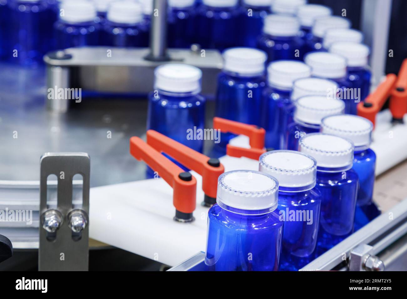 bottiglia di plastica blu sulla linea di produzione del nastro trasportatore presso la macchina di riempimento in fabbrica medica. produzione farmaceutica. Foto Stock