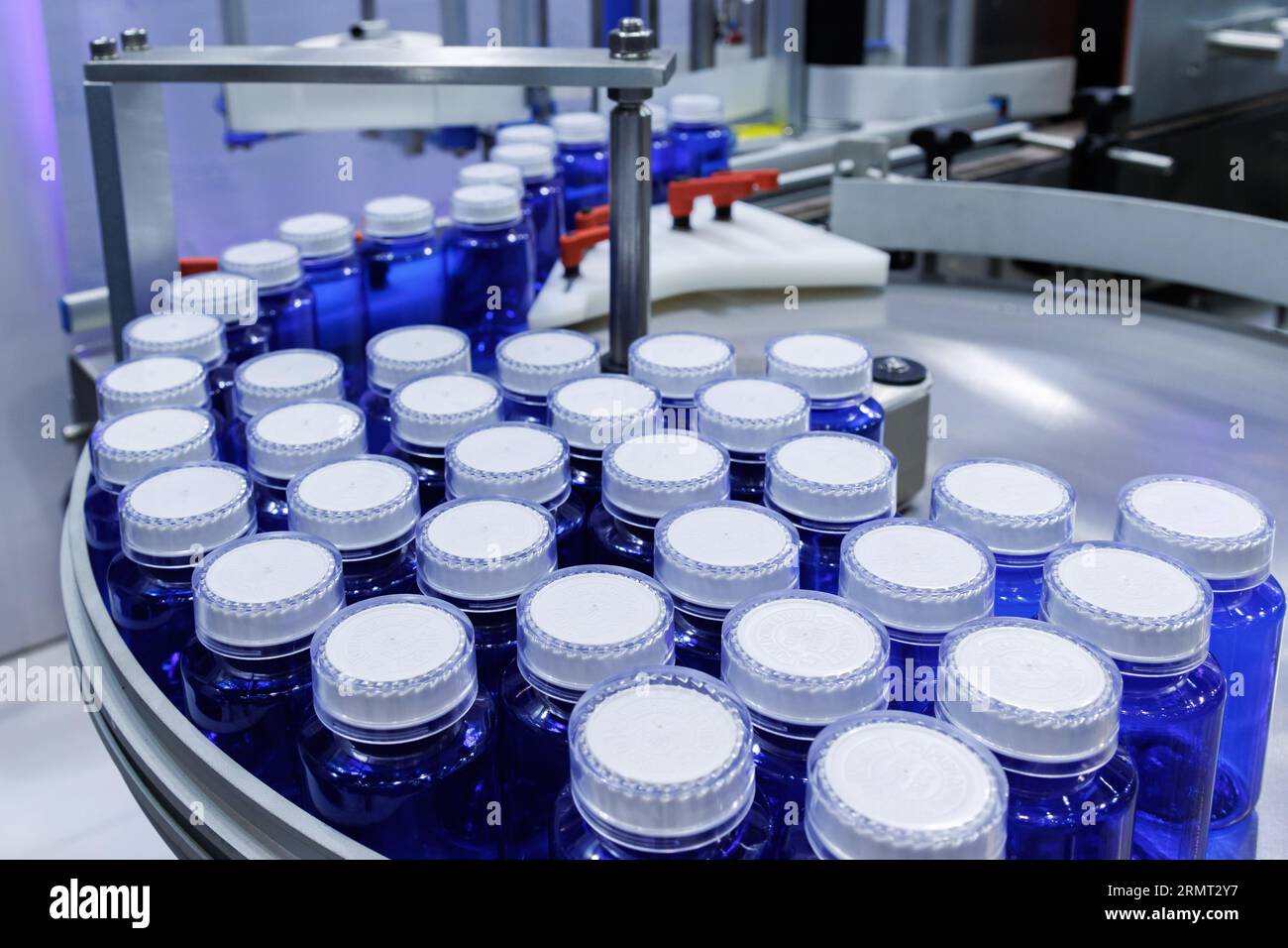 bottiglia di plastica blu sulla linea di produzione del nastro trasportatore presso la macchina di riempimento in fabbrica medica. produzione farmaceutica. Foto Stock