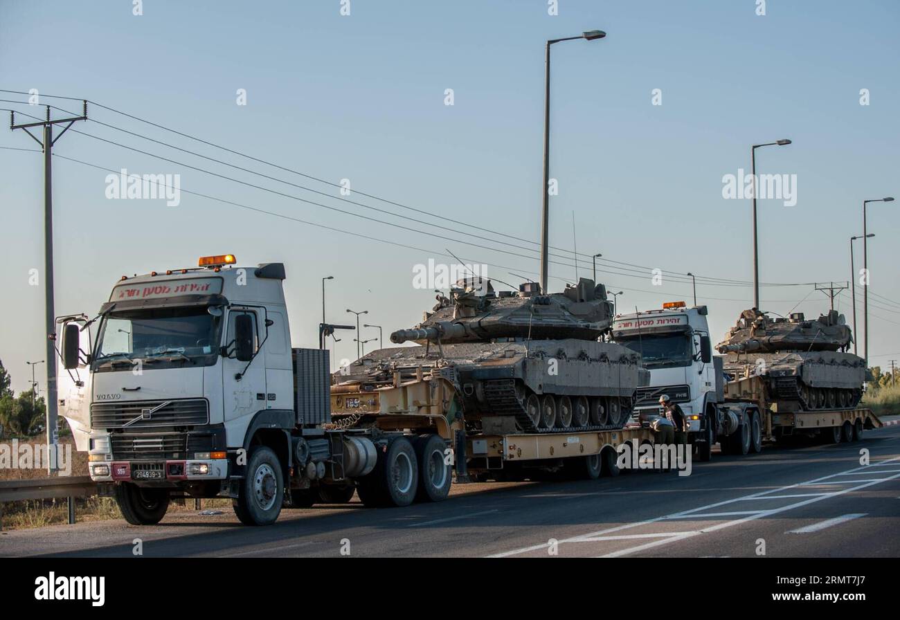 (140820) -- FRONTIERA DI GAZA, 20 agosto 2014 -- la gente ripara un camion che trasporta un carro armato Merkava sulla strada nel sud di Israele al confine con la Striscia di Gaza, il 20 agosto 2014. Israele intensificherà l'offensiva nella Striscia di Gaza fino a quando il lancio di razzi da lì in Israele si fermerà, ha detto mercoledì il primo ministro Benjamin Netanyahu, in risposta ai rinnovati attacchi missilistici di Gaza contro Israele centrale e meridionale all'inizio della giornata. ) ISRAELE-GAZA-OFFENSIVA-RAFFORZAMENTO LixRui PUBLICATIONxNOTxINxCHN frontiera di Gaza 20 agosto 2014 celebrità riparare un camion che trasporta un carro armato Merkava sulla strada nel sud di Israele borde ring T Foto Stock