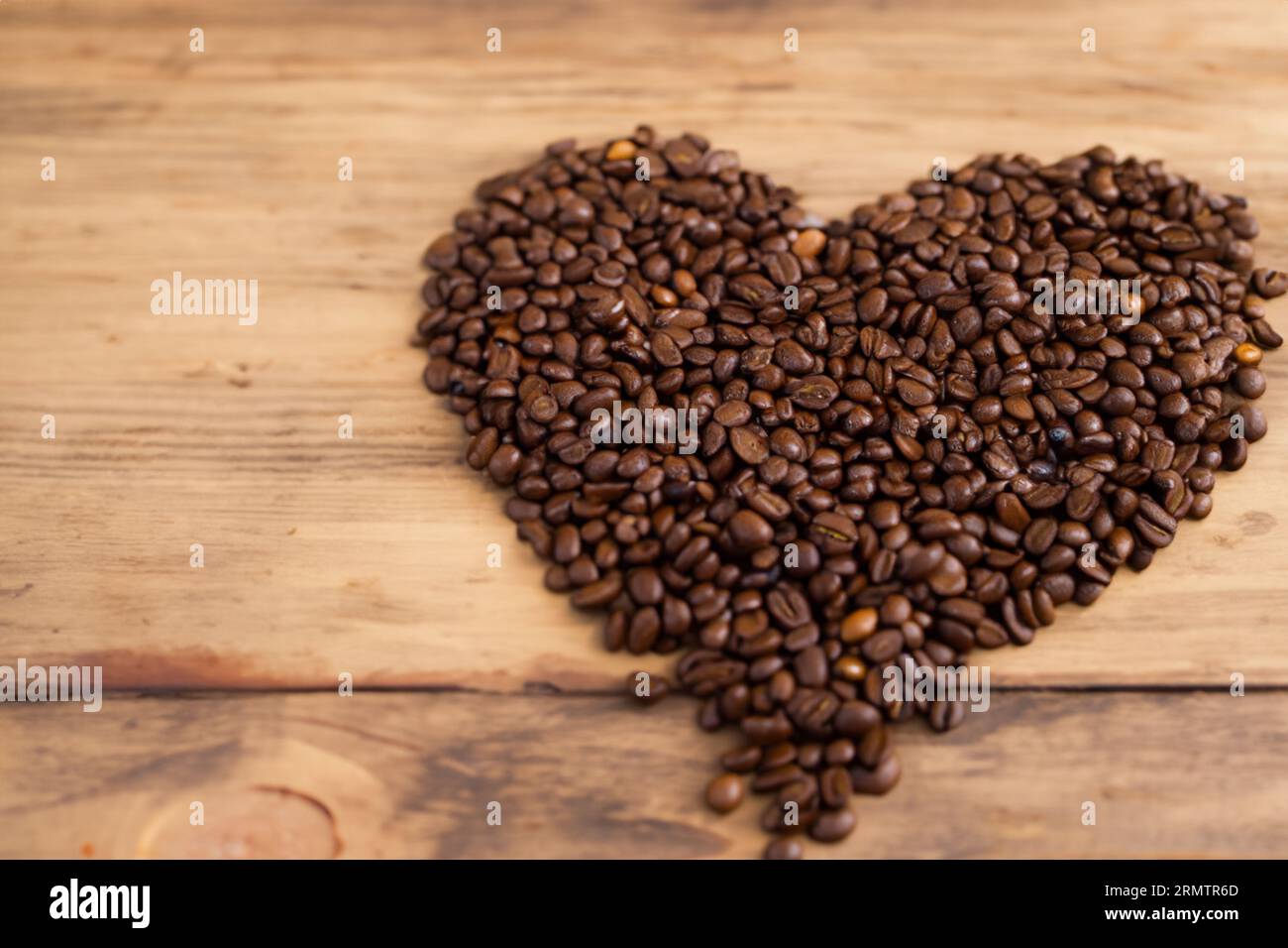 chicchi di caffè biologici disposti a forma di cuore sul vecchio tavolo di legno Foto Stock