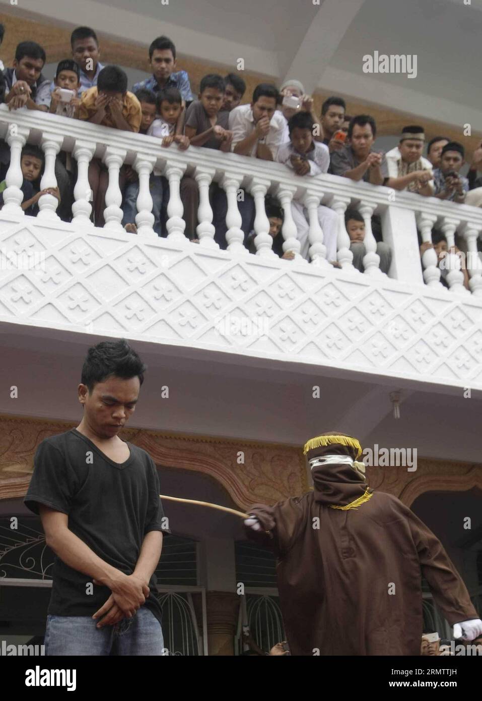 (140919) -- ACEH, 19 settembre 2014. -- Un funzionario della Sharia frena un uomo condannato per gioco d'azzardo con una canna da rattan durante una fustigazione pubblica ad Aceh, Indonesia, il 19 settembre 2014. L'amministrazione provinciale di Aceh, nel nord dell'isola indonesiana di Sumatra, ha approvato una legge chiamata Qanun Jinayat implementato una versione della legge islamica della Sharia dal 2001. INDONESIA-LEGGE ACEH-SHARIA Junaidi PUBLICATIONxNOTxINxCHN Aceh 19 settembre 2014 un funzionario della Sharia un uomo condannato per gioco d'azzardo con una canna di rattan durante un pubblico ad Aceh Indonesia IL 19 settembre 2014 l'Amministrazione Provinciale di Aceh Foto Stock