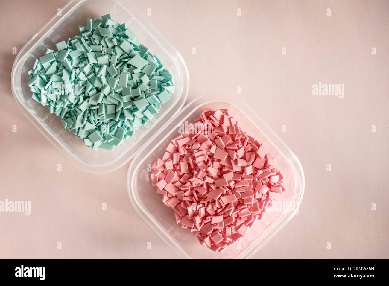 Una pila di plastica - piccoli pezzi di plastica dura, di colore rosa e blu, destinati a ulteriori lavorazioni Foto Stock