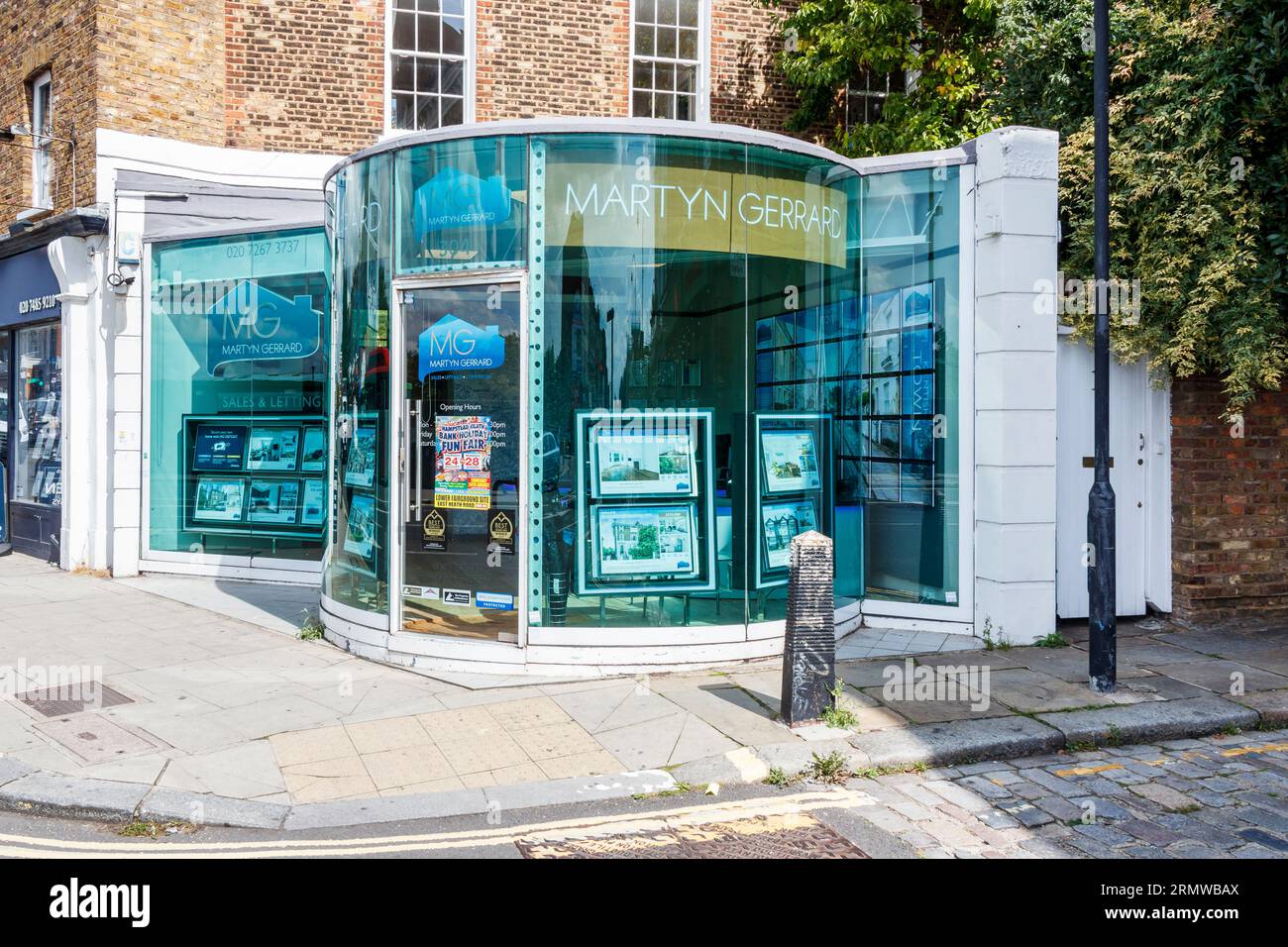 Una filiale degli agenti immobiliari di Martyn Gerrard con un ufficio con facciata in vetro dalla forma insolita a Kentish Town, Londra, Regno Unito Foto Stock