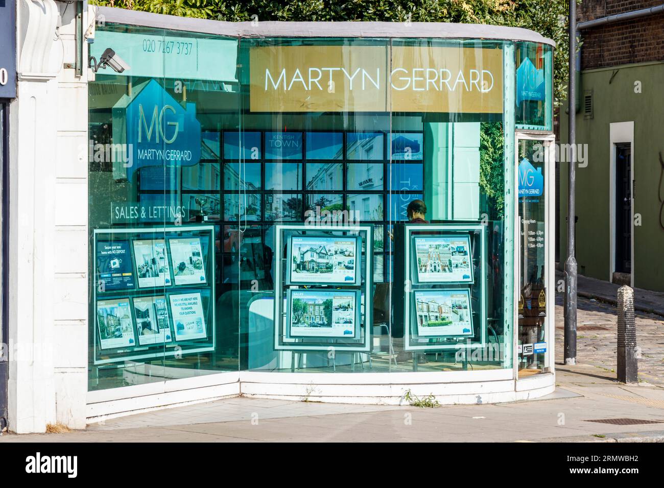 Una filiale degli agenti immobiliari di Martyn Gerrard con un ufficio con facciata in vetro dalla forma insolita a Kentish Town, Londra, Regno Unito Foto Stock