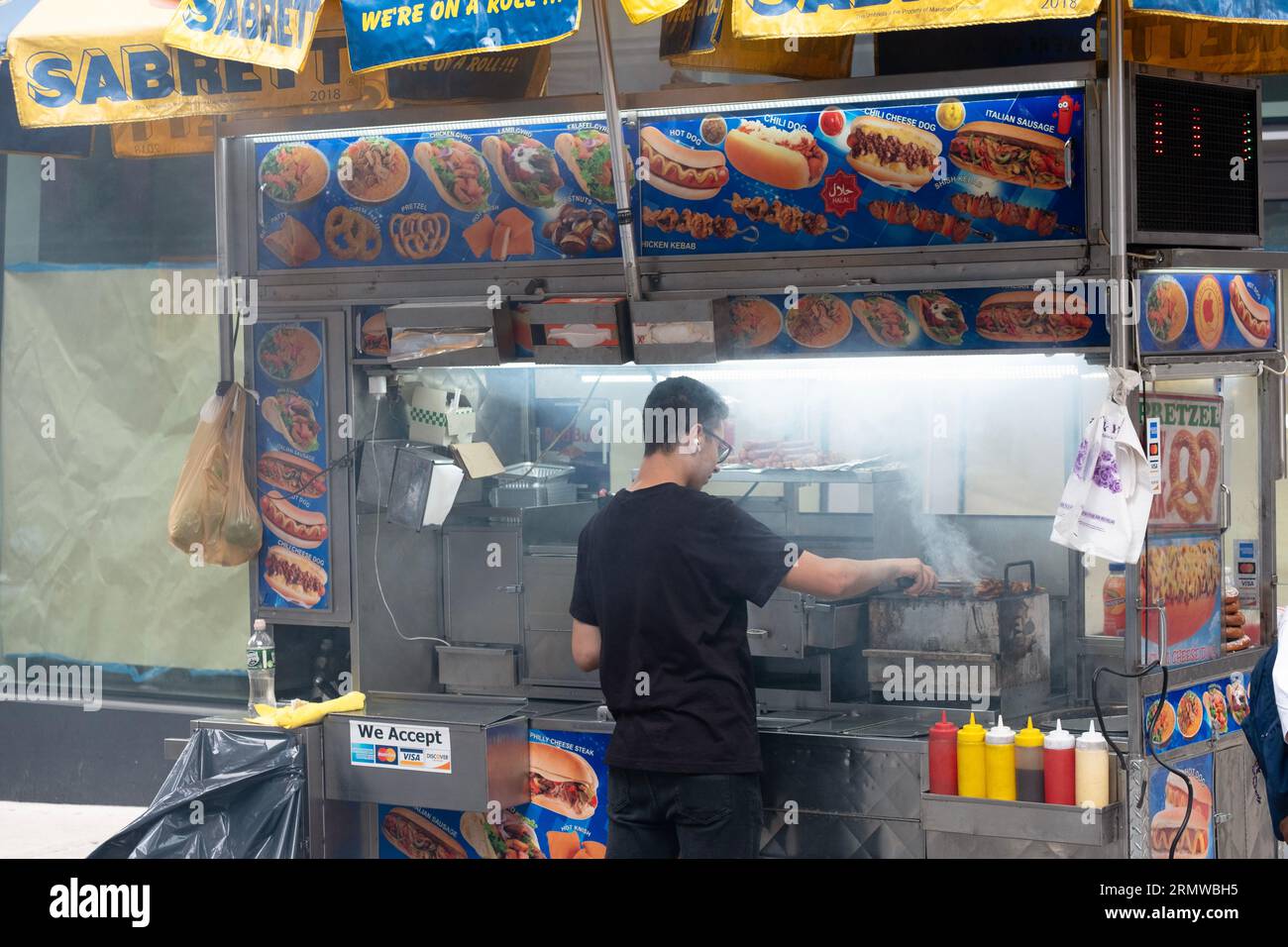 Un venditore di cibo appena fuori la 7th Avenue sulla West 37th Street grigia carne in un mare di fumo. A Midtown Manhattan. Foto Stock