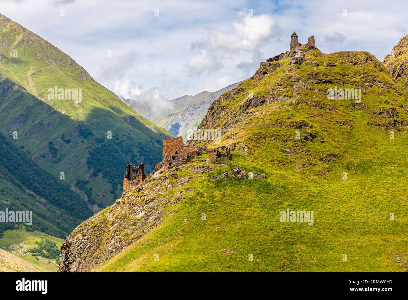 Torri rovinati si ergono su una cresta ripida sul sentiero da Girevi a Chontio nel Tusheti, nella municipalità di Akhmeta, regione di Kakheti, Georgia, forse il villaggio fortificato di Hegho. Due torri si innalzano sulla cima. Più in basso lungo la cresta si trovano le mura di un edificio più grande con un ampio moncone di torre. A sinistra, il pendio erboso scende ripido nella valle. Dietro ci sono pendici montuose boschive e una valle sotto le nuvole. Il villaggio fortificato abbandonato di Hegho si trova sopra la confluenza di due torrenti. Secondo la leggenda, gli aggressori hanno appreso da un maestro costruttore del Dagestan che una pietra bianca conteneva il vi Foto Stock