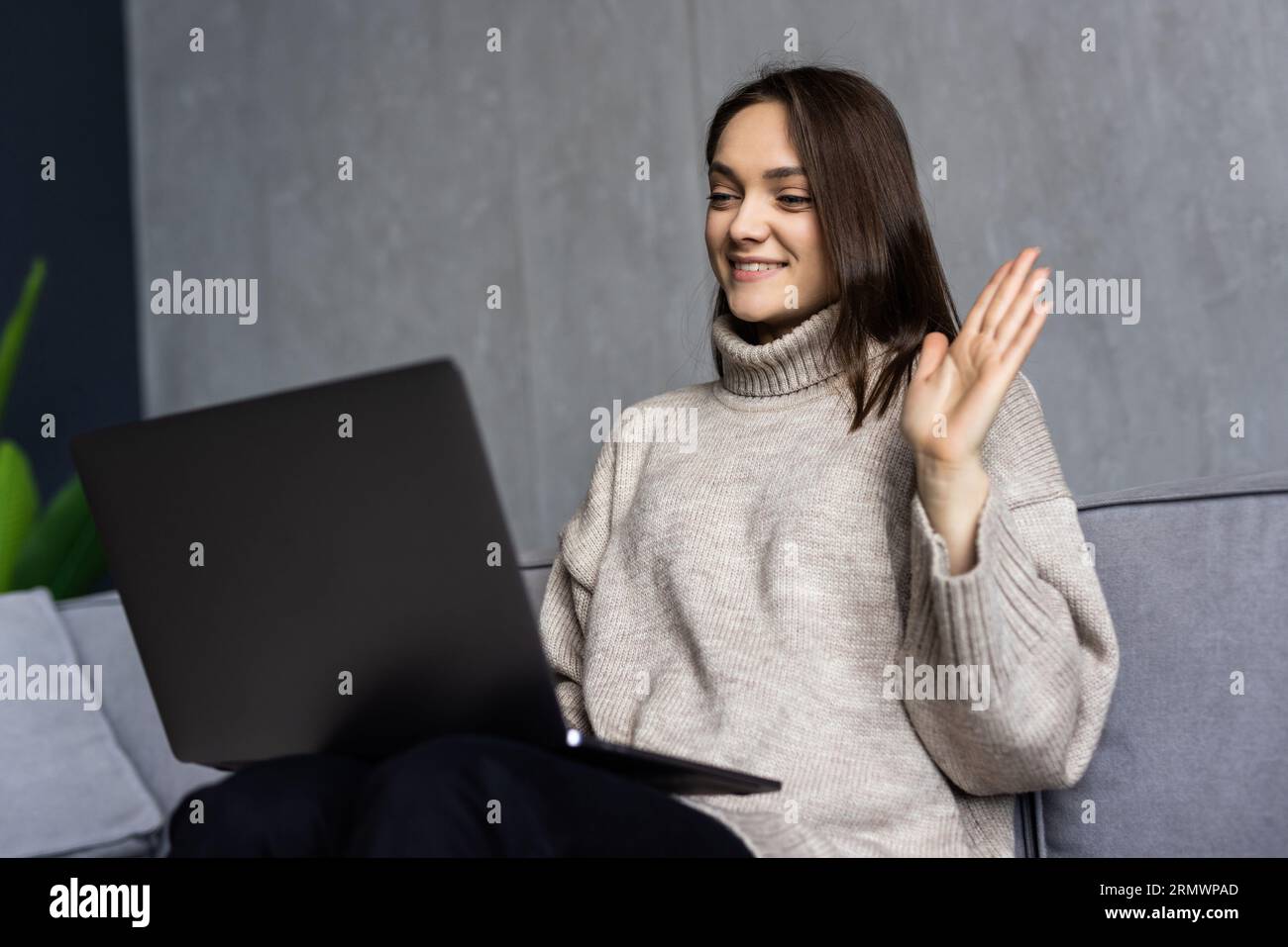 Giovane donna che ha una videochiamata via computer portatile in ufficio Foto Stock