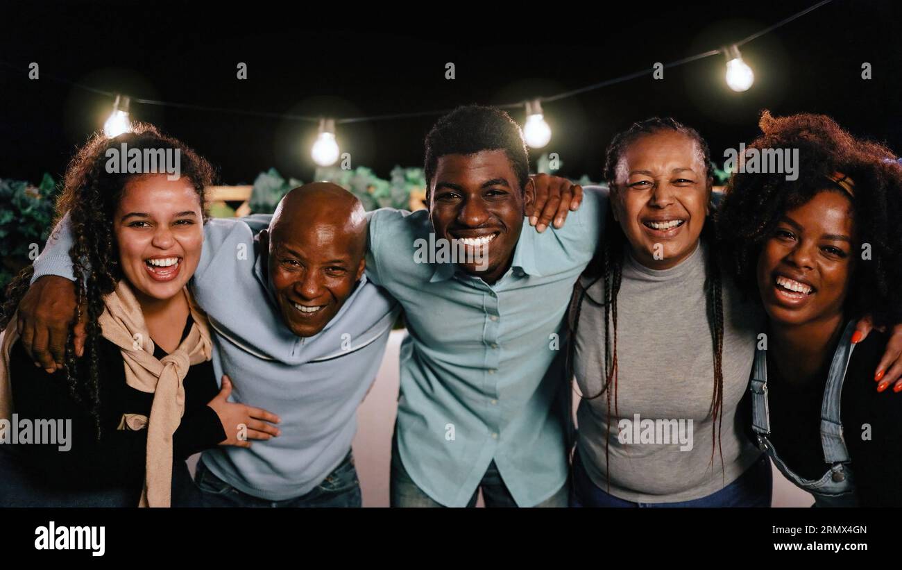 Felice famiglia africana che si diverte ad abbracciare insieme all'aperto durante la festa serale in casa di vacanza - concetto di celebrazione e relazione - Focus su Left Daughter Foto Stock