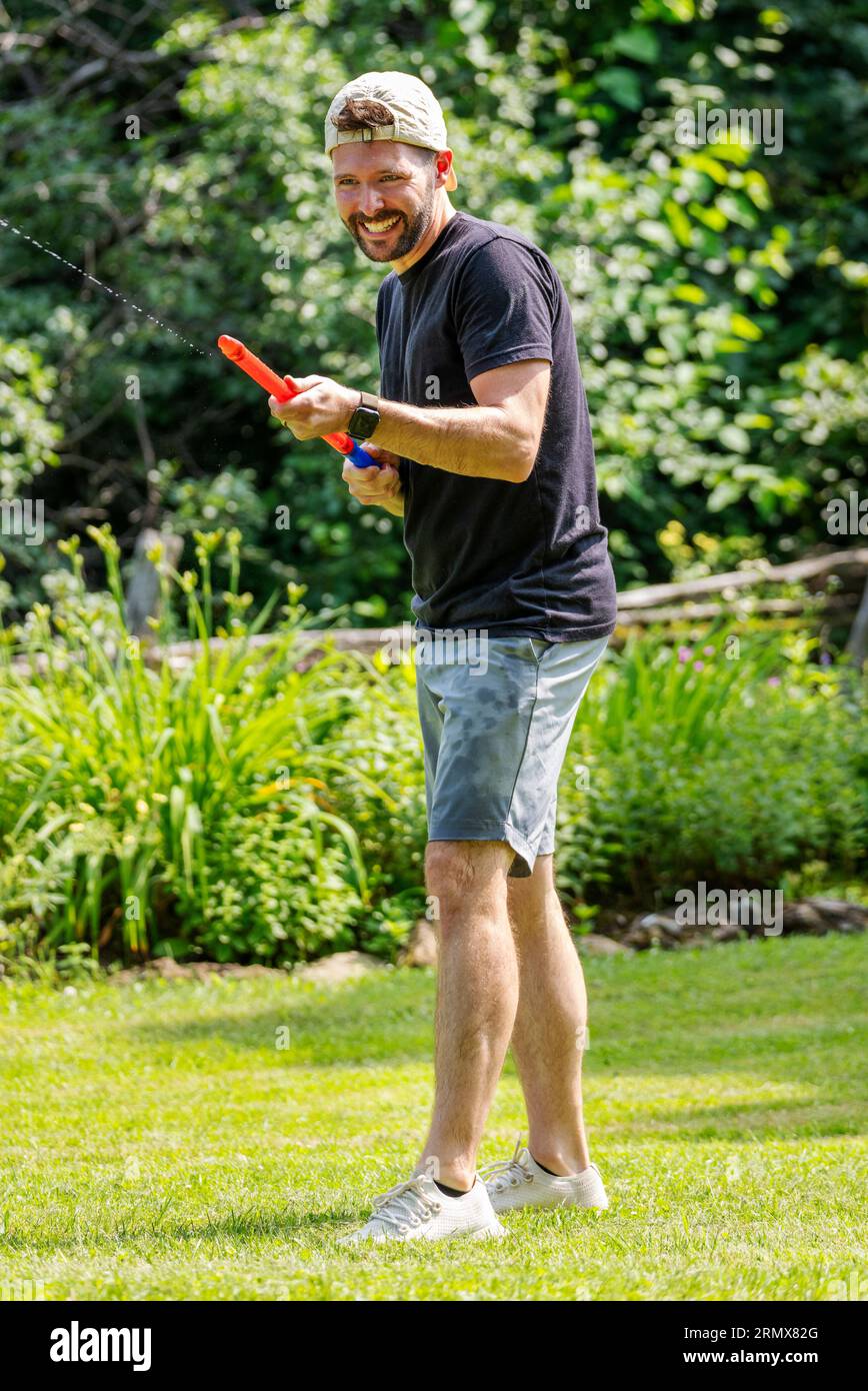 Uomo adulto che gioca con i giochi d'acqua in una calda giornata estiva Foto Stock