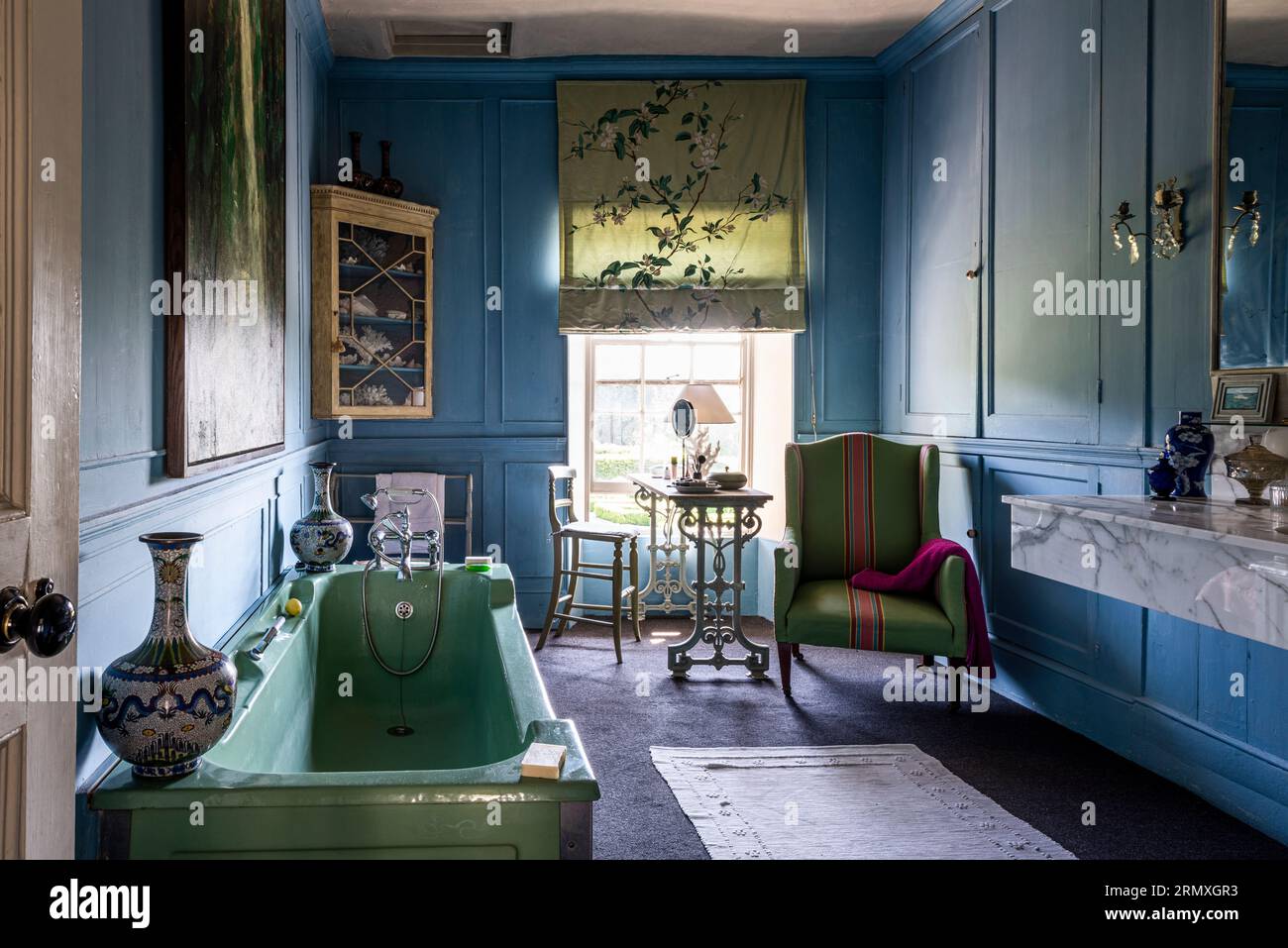 Sedia verde e vasca da bagno in bagno rivestito in pannelli di un loft fiorito del XIX secolo vicino a Penzance in Cornovaglia, Regno Unito Foto Stock